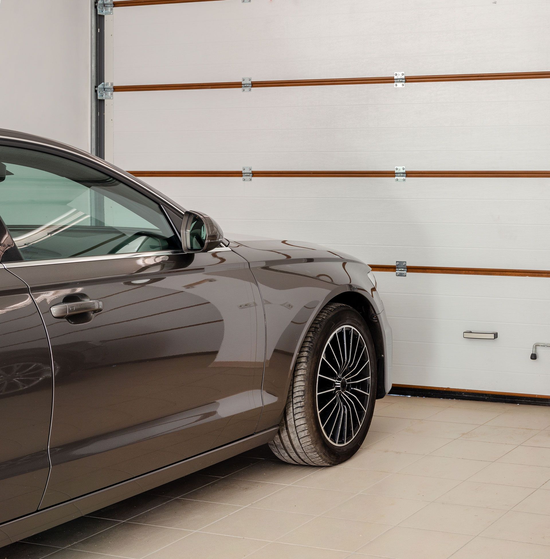 A car is parked in a garage next to a garage door.