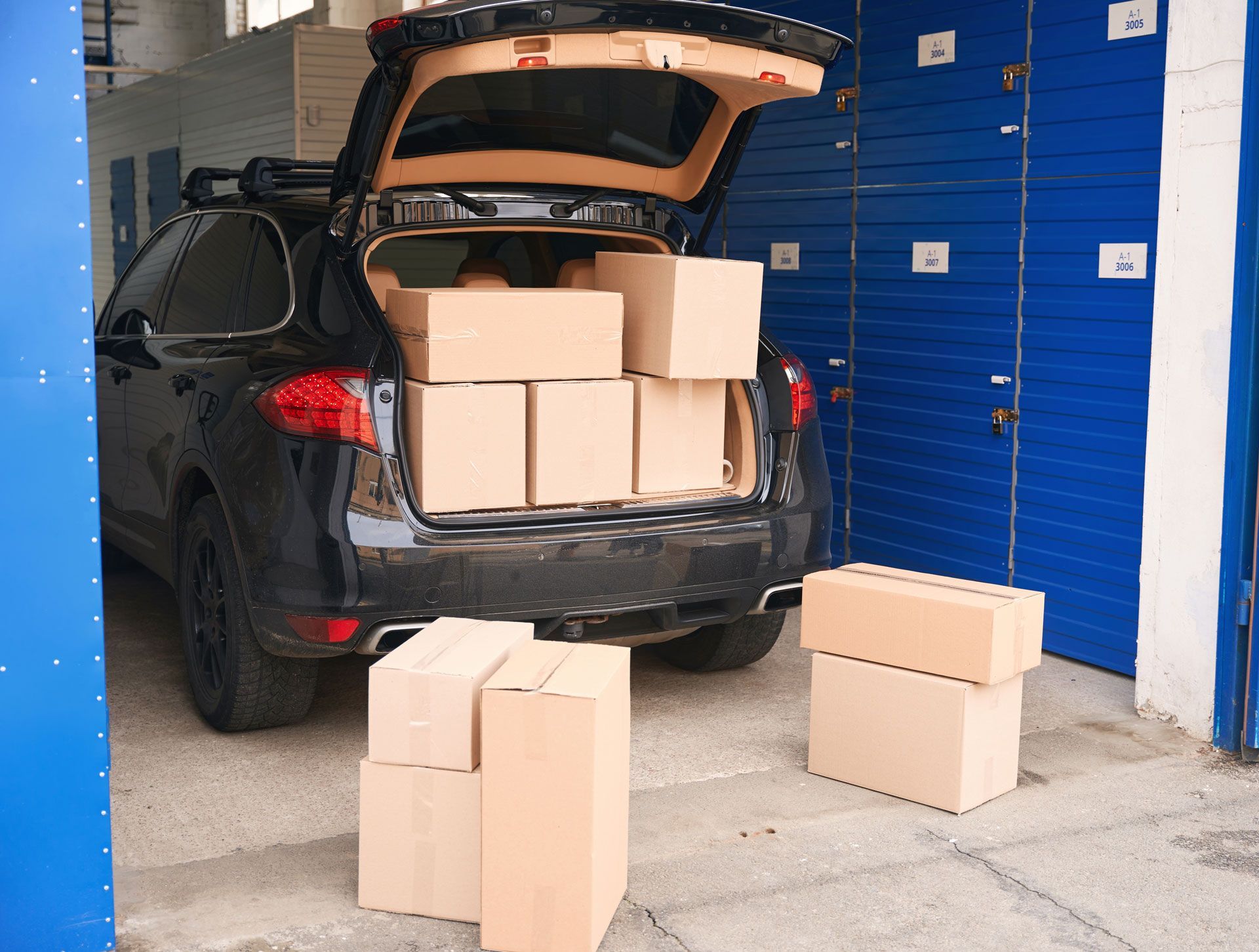 The back of a car is filled with cardboard boxes.