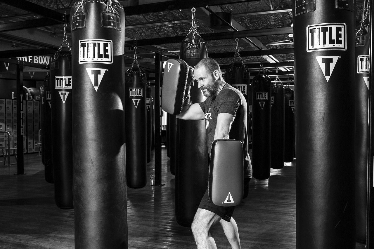 A man is standing next to a boxing bag in a gym.