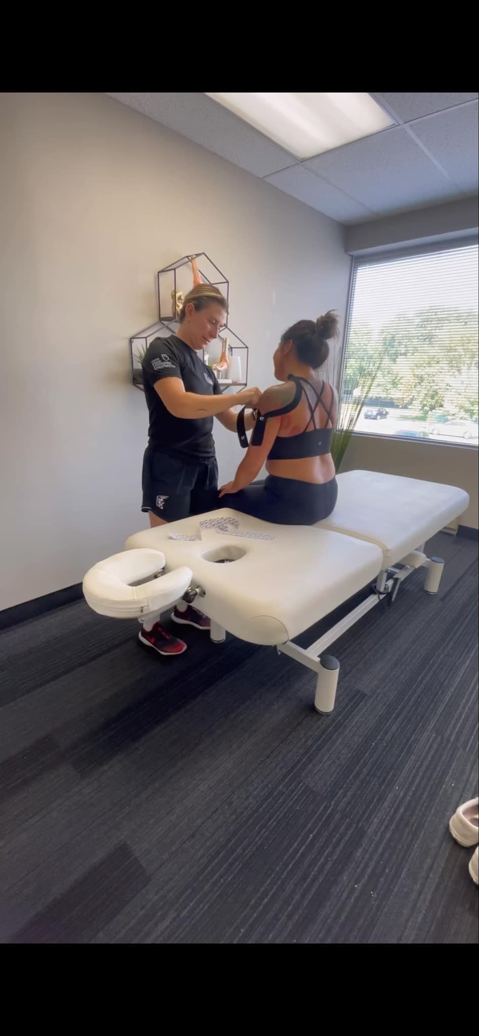 A woman is sitting on a table getting a massage from a man.