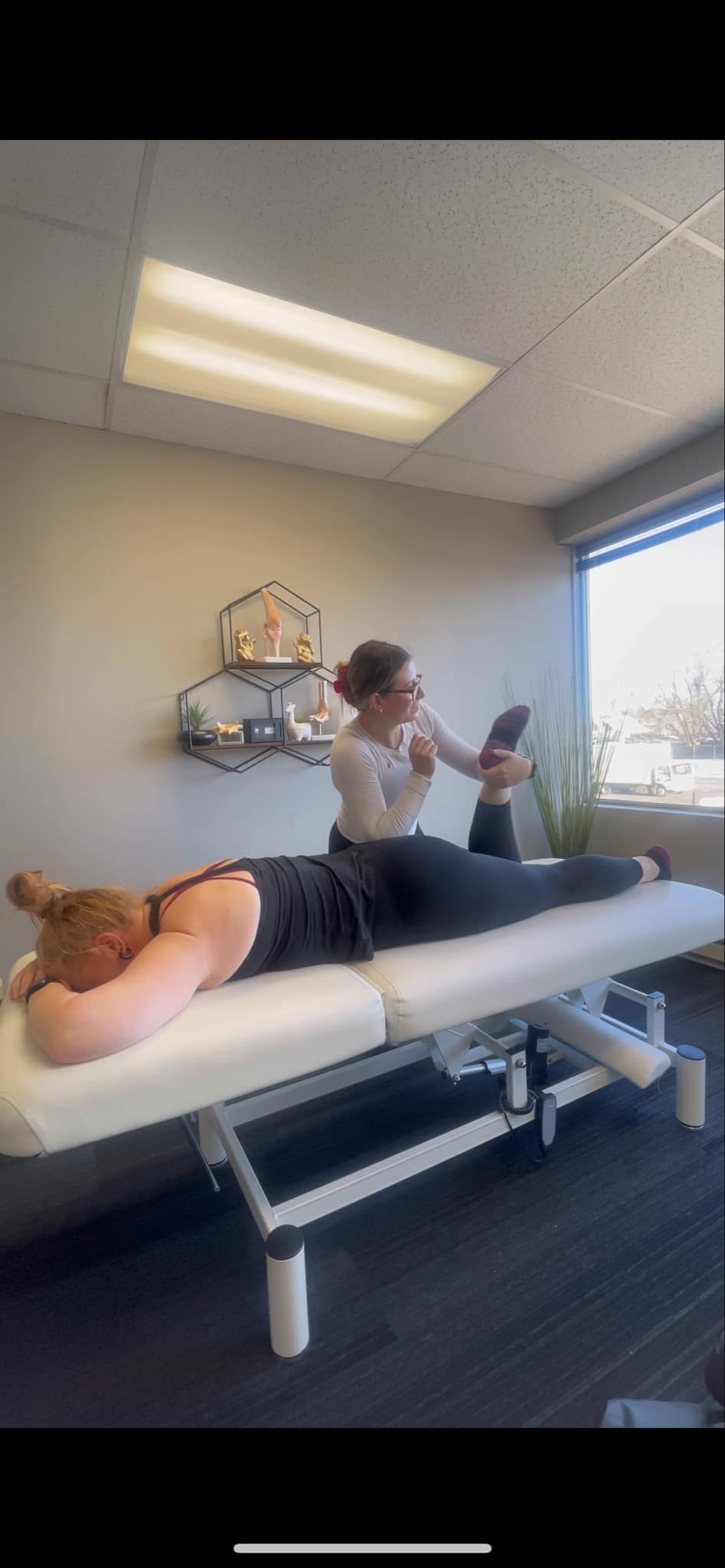 A woman is laying on a table getting a massage.