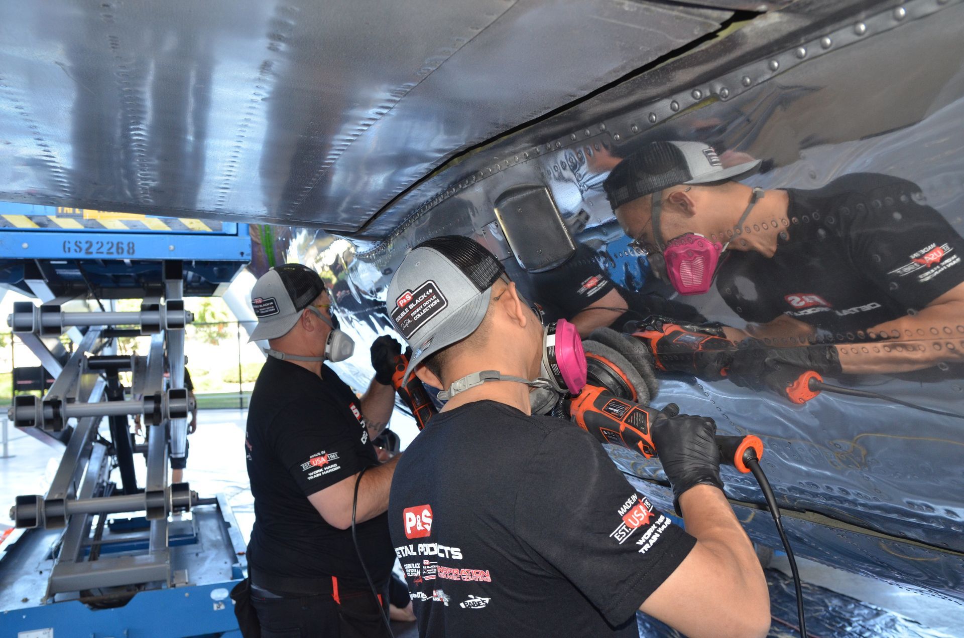 Two men are working on a boat in a garage.