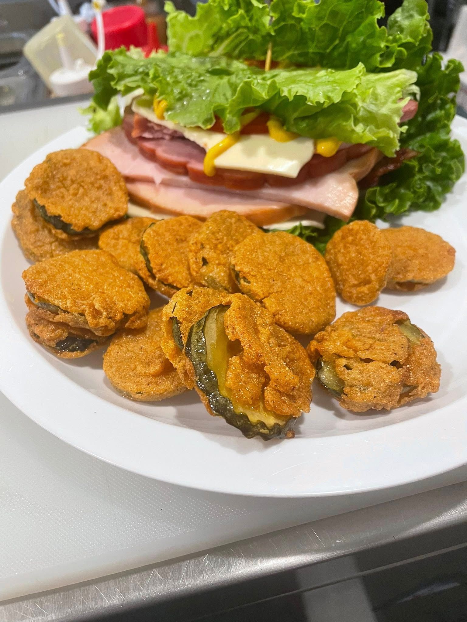 Plate of fried pickles and a lettuce wrap sandwich with ham and cheese.