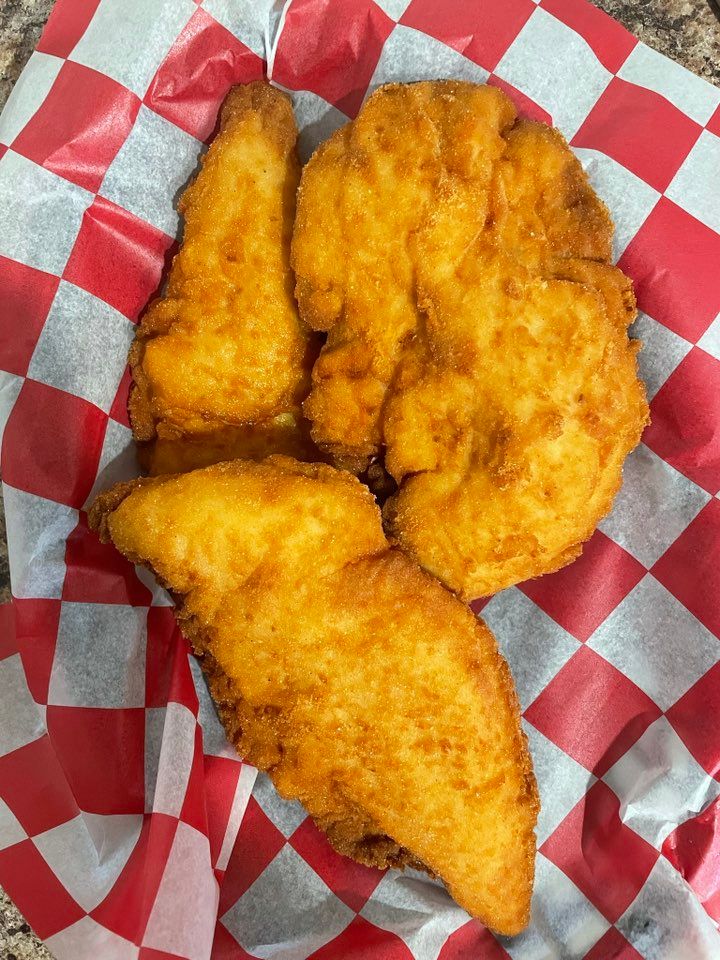 Fried chicken pieces in a red and white checkered paper basket. The chicken is golden-brown and crispy.