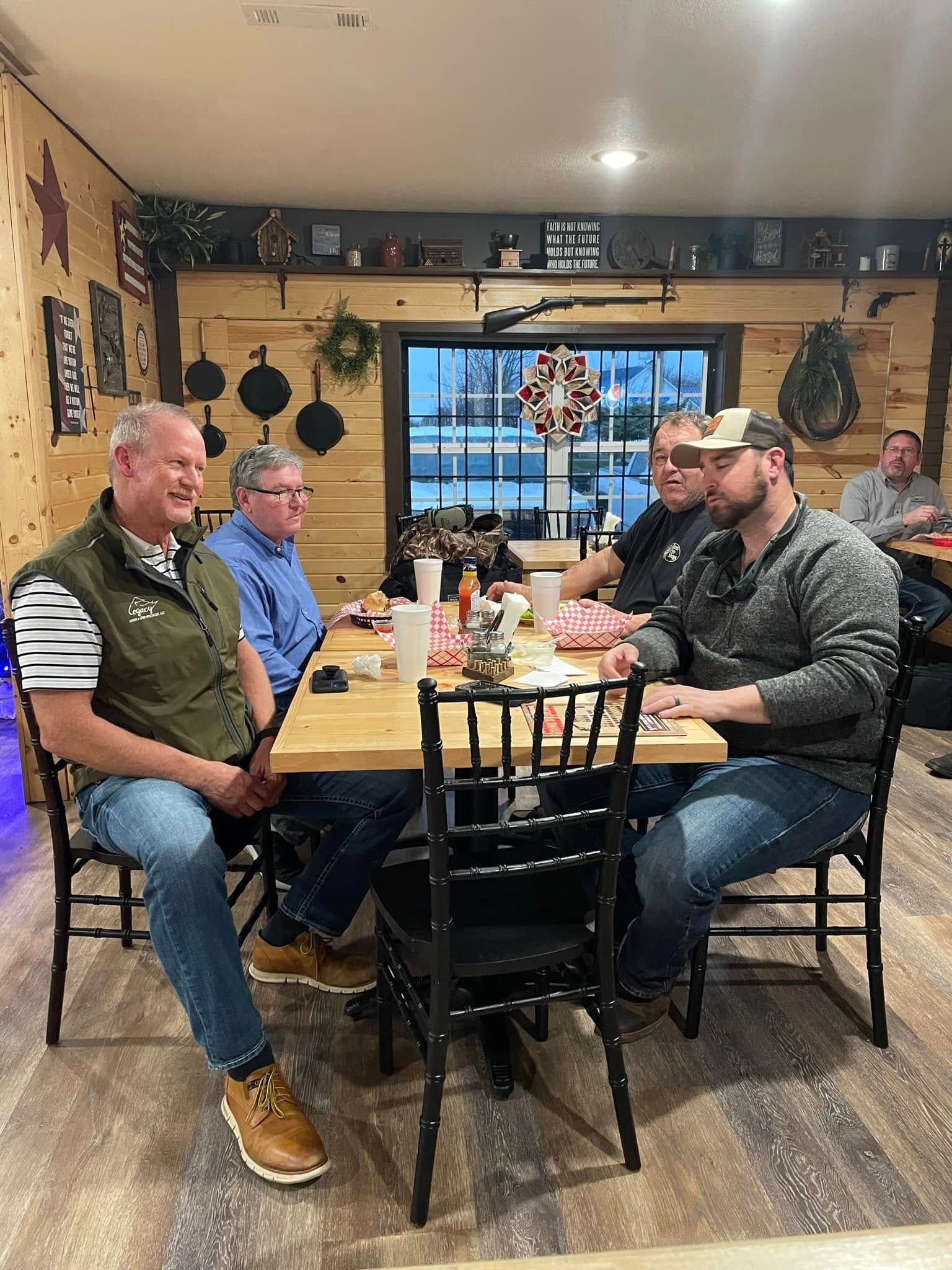 A group of men are sitting at tables in a restaurant.