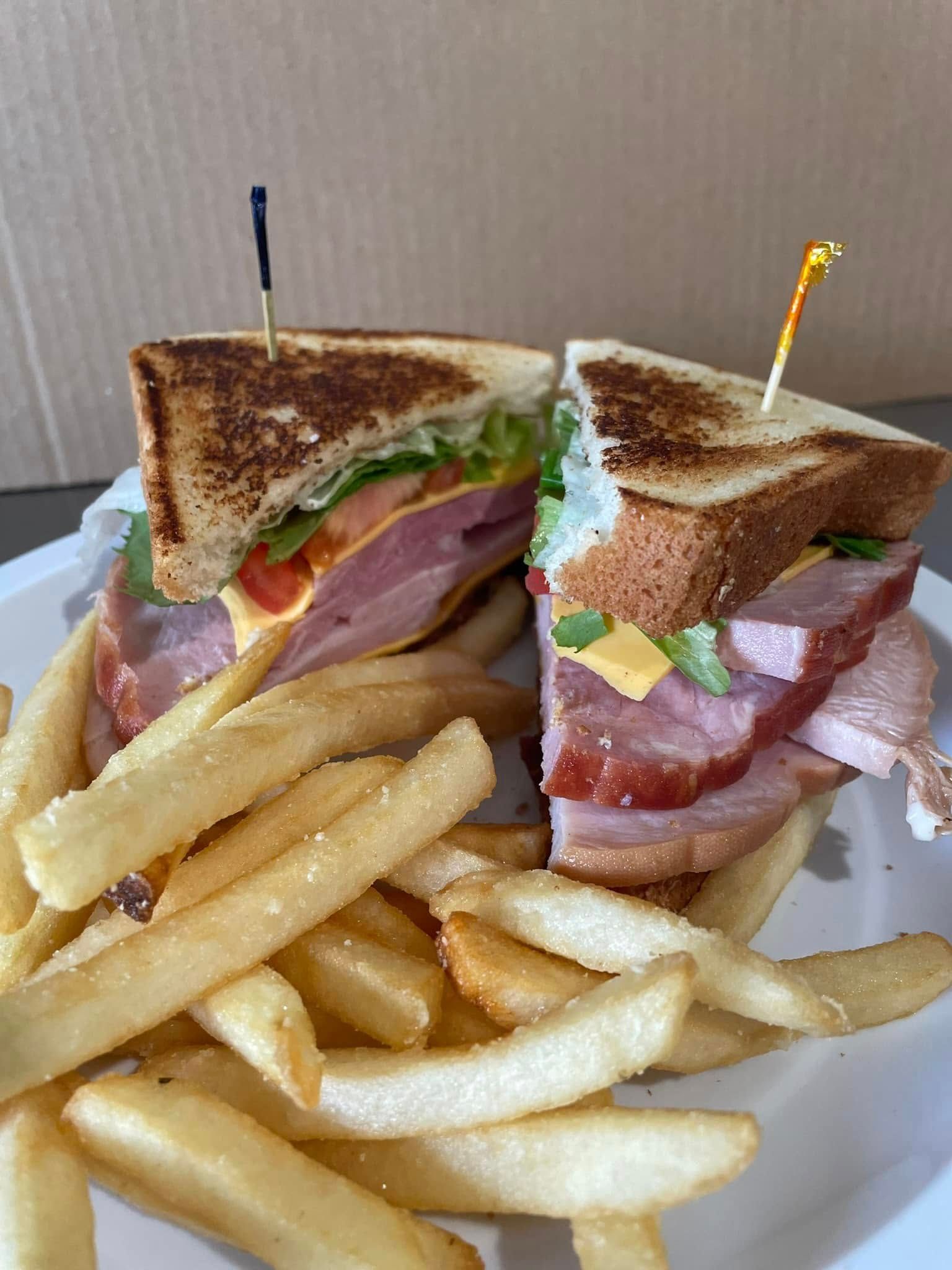 A club sandwich and french fries on a white plate.