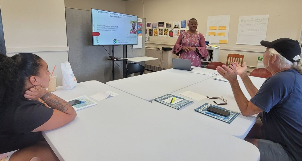 A woman leads a presentation to two seated people at a table.