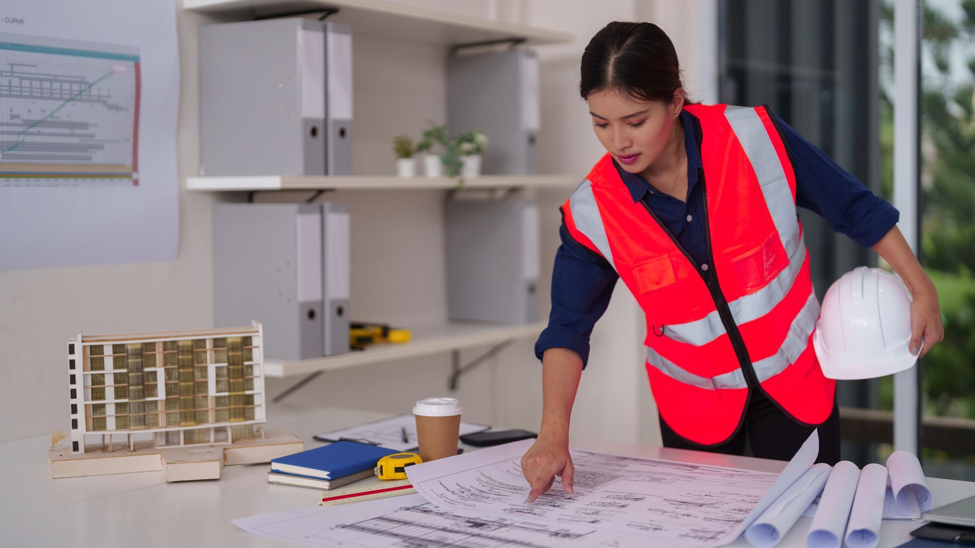Adult woman reviews building blueprints planning construction project professional.
