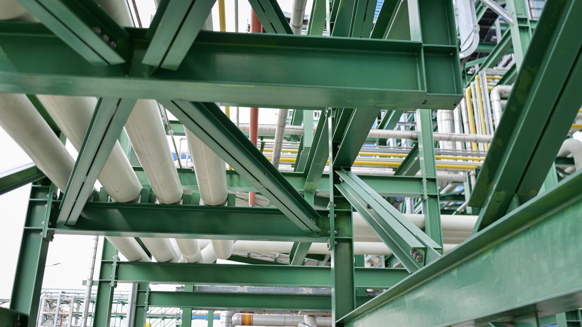 Green industrial steel structure frame with white pipelines.