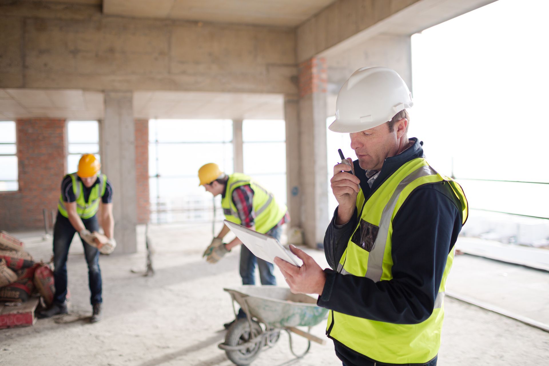 Structural engineering in progress, highlighting worker using tablet and walkie talkie on site. Structural engineering in progress, highlighting worker using tablet and walkie talkie on site.