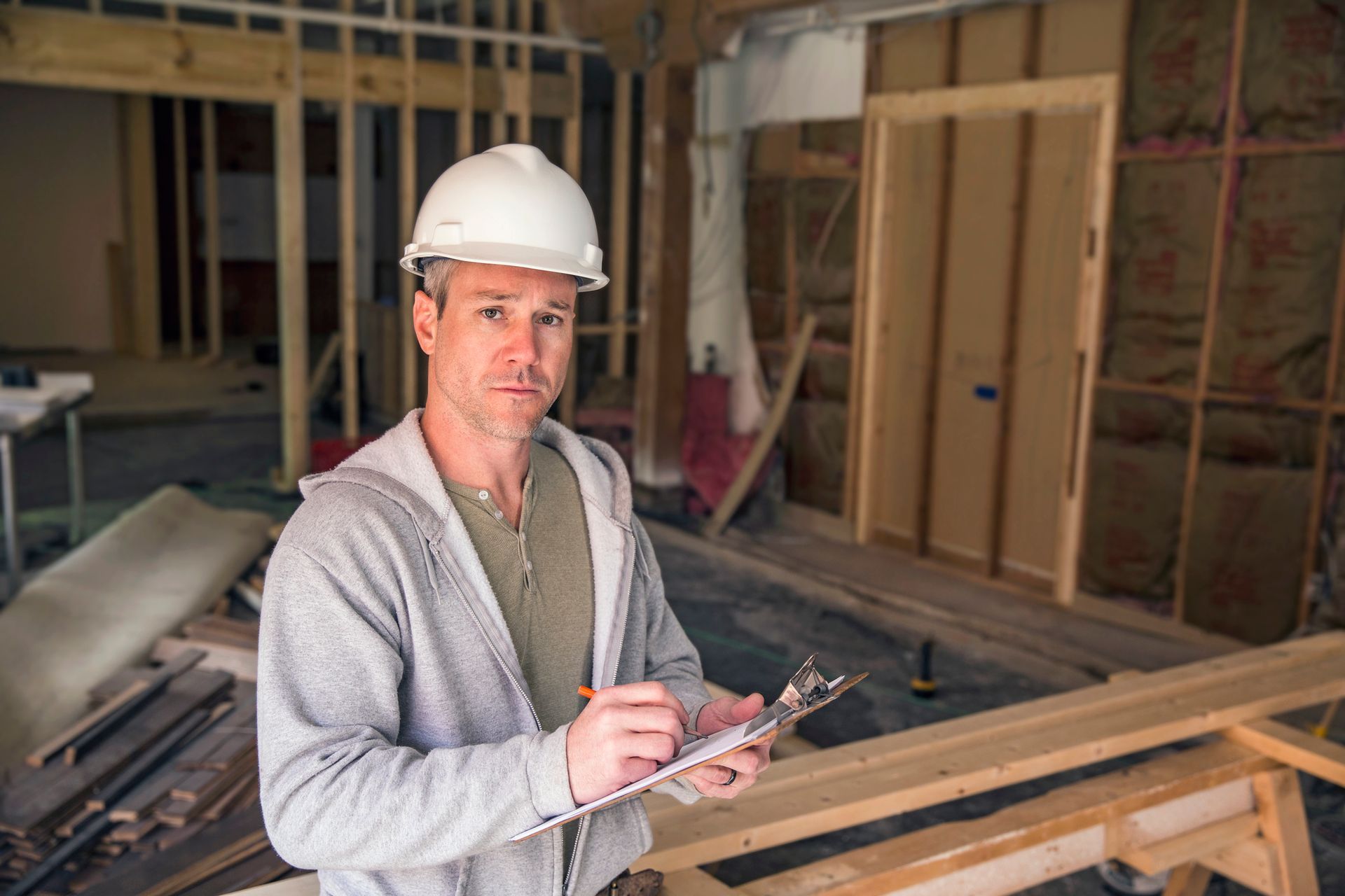 An engineer holding a clipboard and pen at work on a new structure.