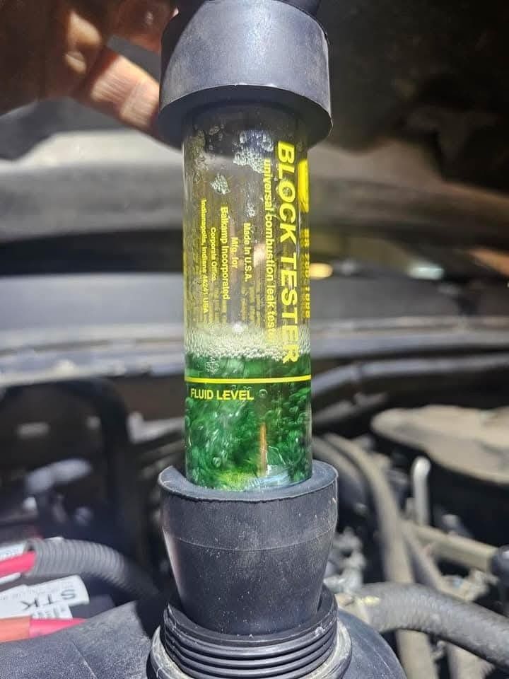 Block test tool detecting coolant presence. Fluid shows a green color in an engine bay.