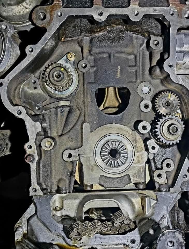 Open view of engine's internal components, including gears, oil pump, and connecting rod. Metal-on-metal construction.