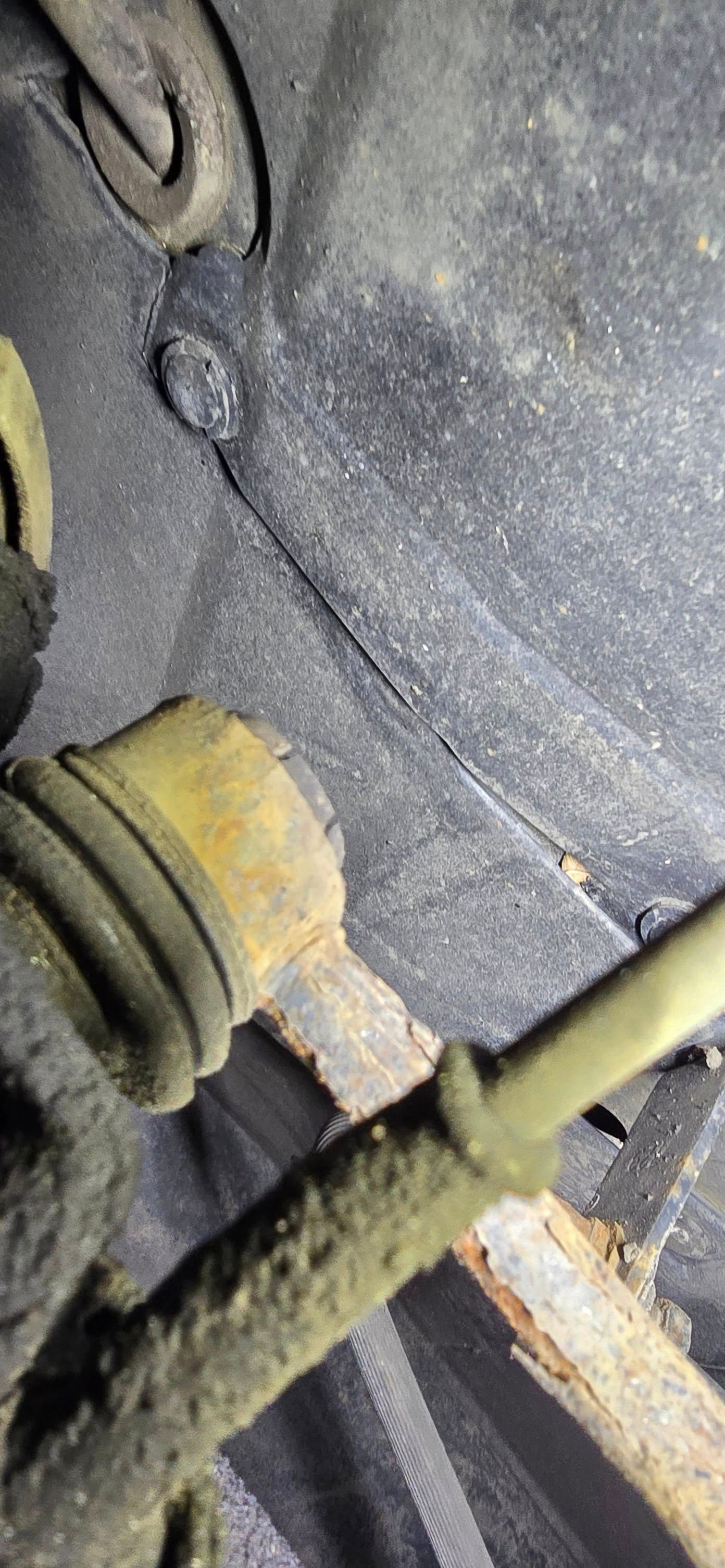Rusty car parts with a rubber boot against a dark background.
