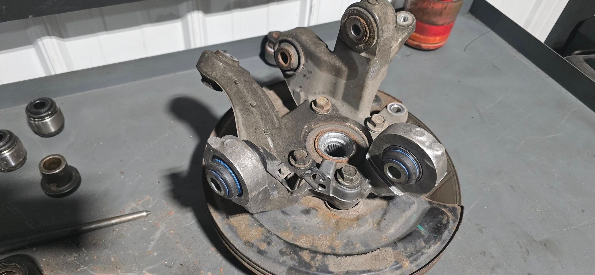 Car suspension components laid out on a gray surface, with nuts and bolts in the foreground.