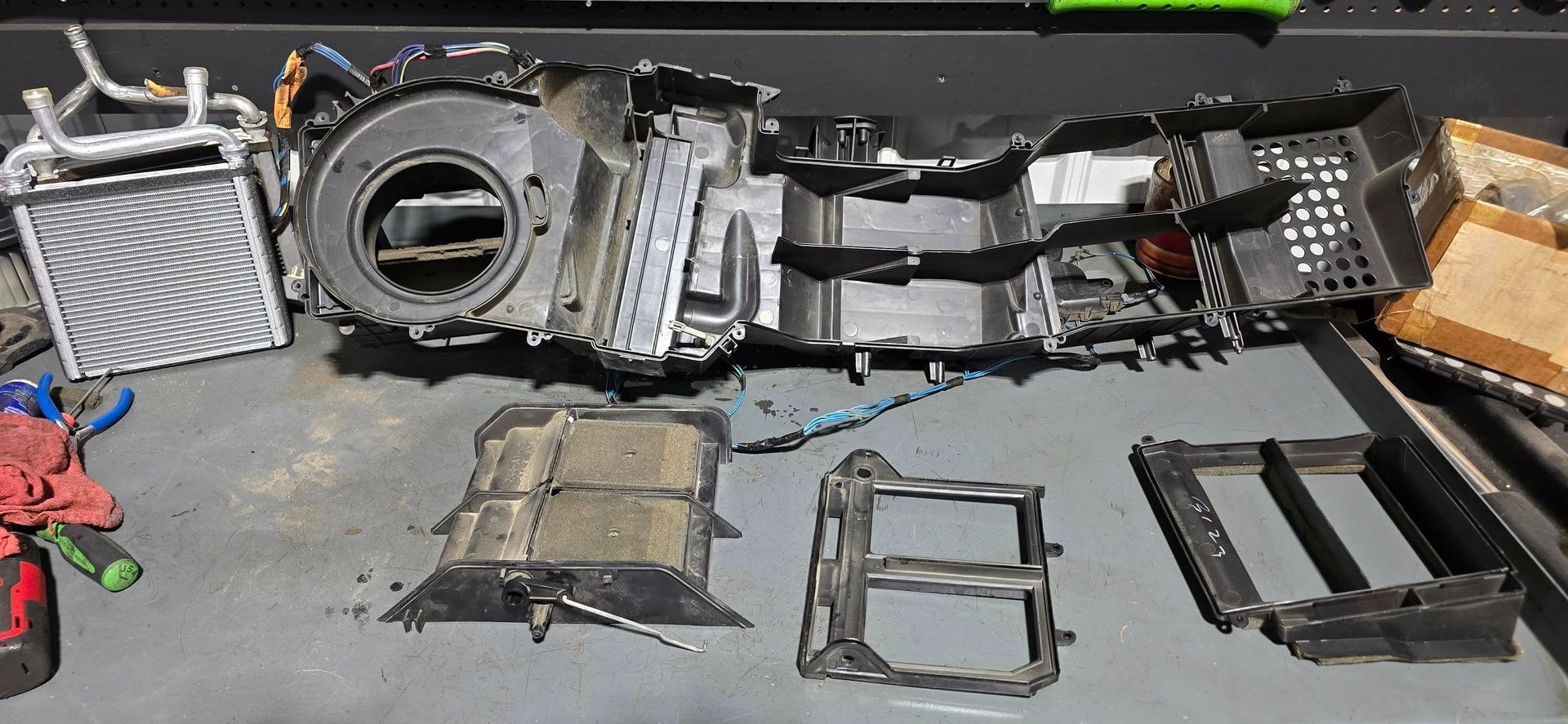 Deconstructed car air conditioning unit parts on a workbench.