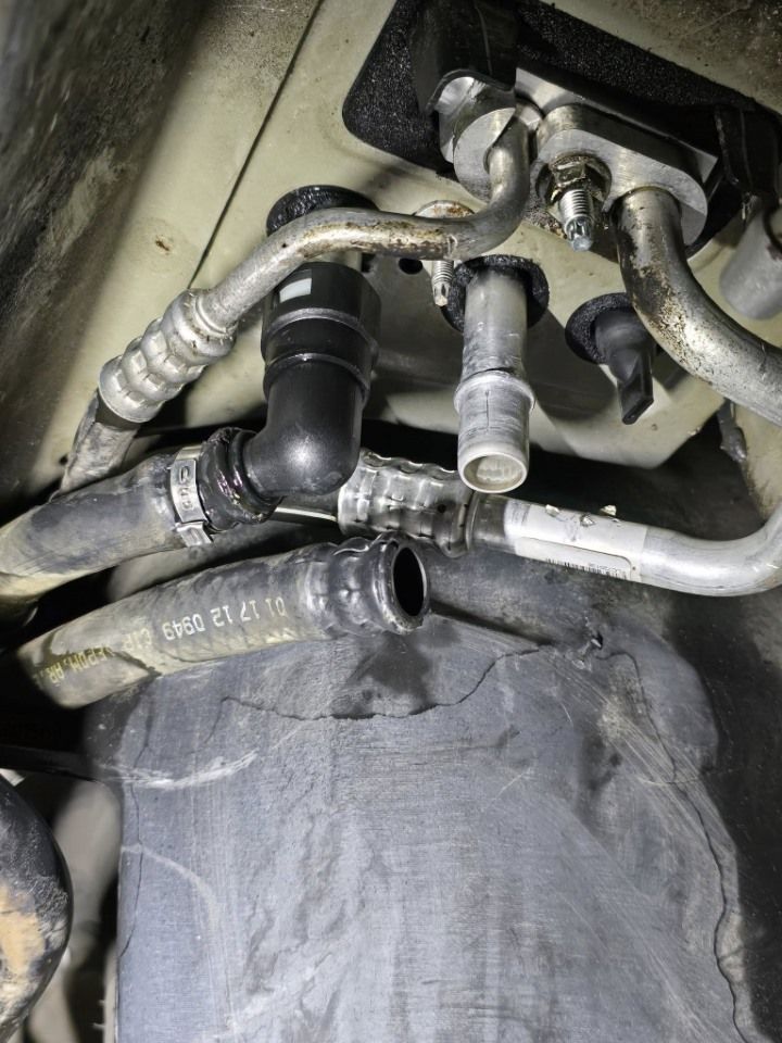 Engine compartment with hoses and connectors, possibly related to a car's air conditioning or heating system.
