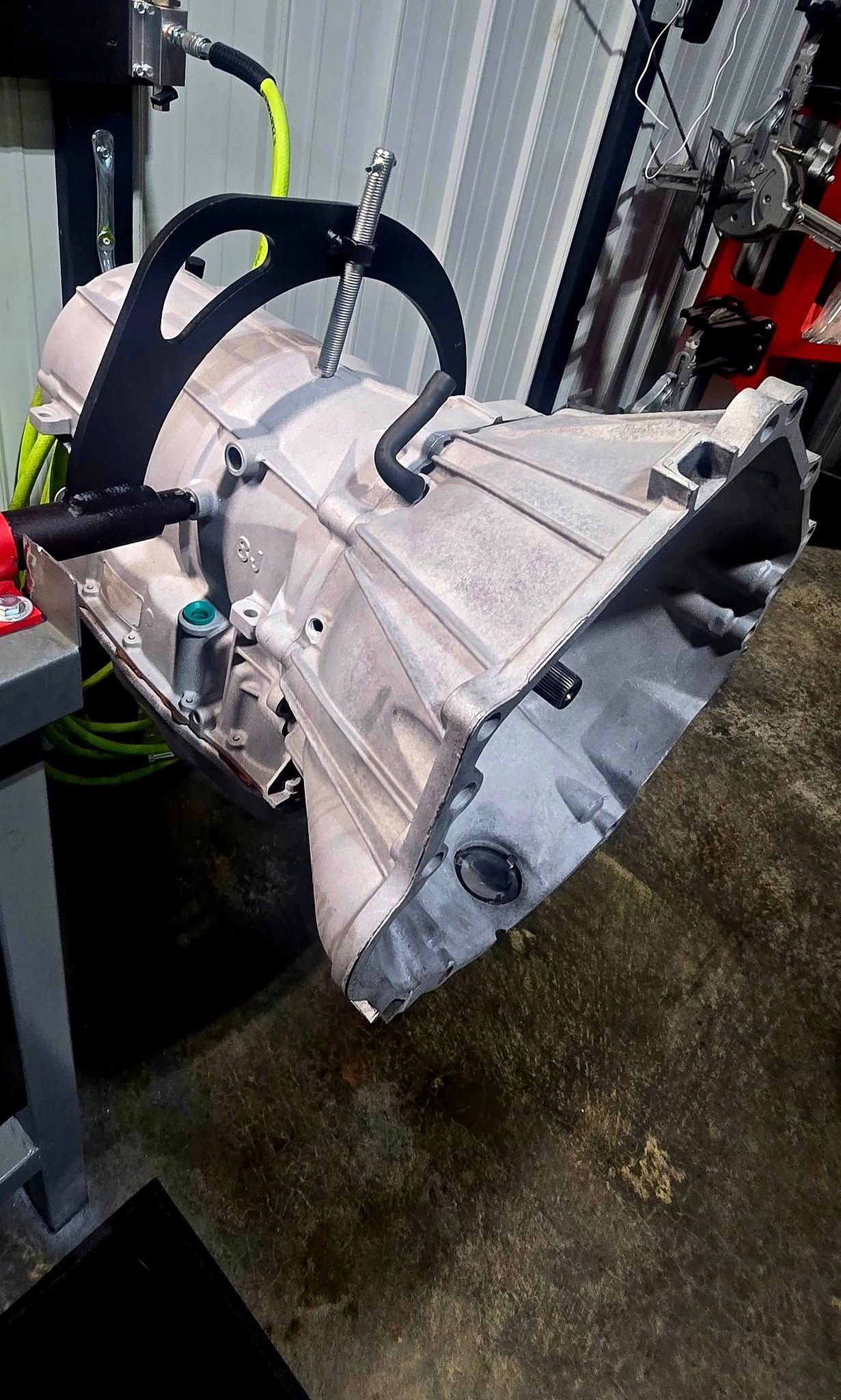Automatic transmission suspended from a lift in a workshop.
