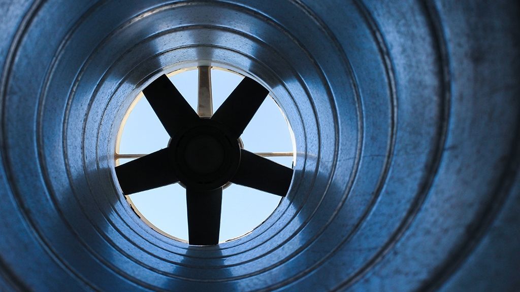 Looking through a metal pipe with a fan in the middle.