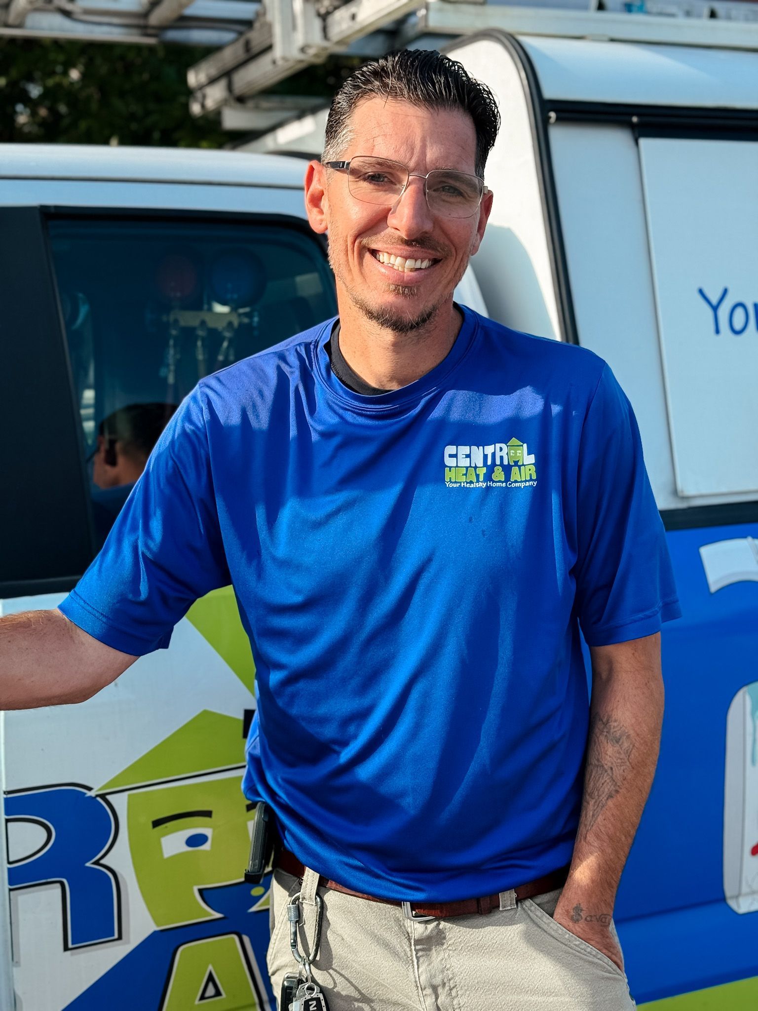 A man wearing a hat and a blue shirt is standing in front of a brick wall.