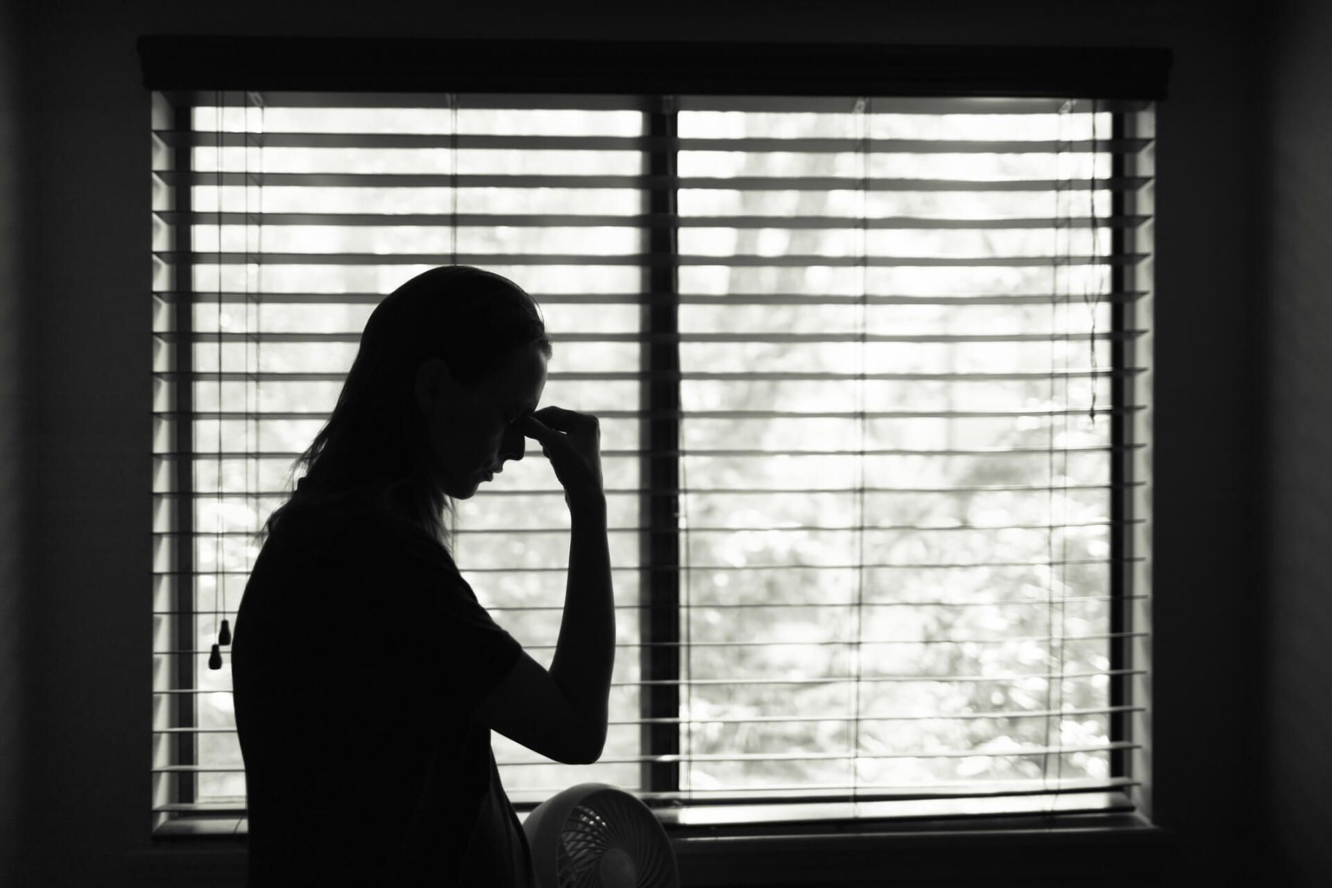 Tired Woman Standing Next to Bedroom Window — Chesapeake, VA — Peterson Law PLC