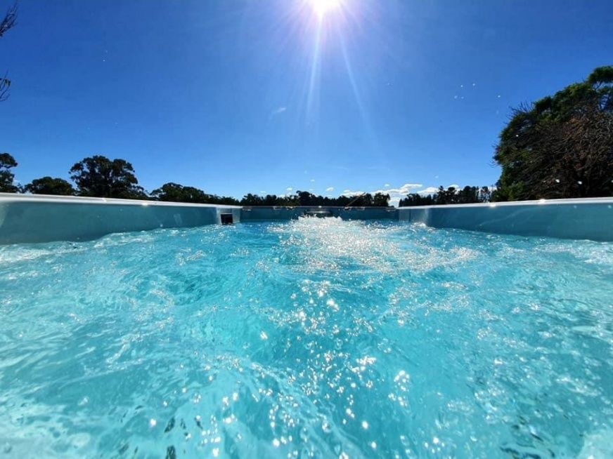A Person Is Swimming In A Swimming Pool On A Sunny Day — Dazzling Blue Pool & Spa Centre Gold Coast in Burleigh Heads, QLD