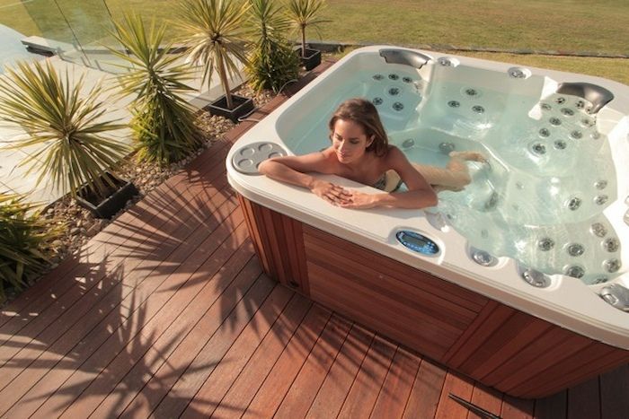 A Woman Is Laying In A Hot Tub On A Deck — Dazzling Blue Pool & Spa Centre Gold Coast in Palm Beach, QLD