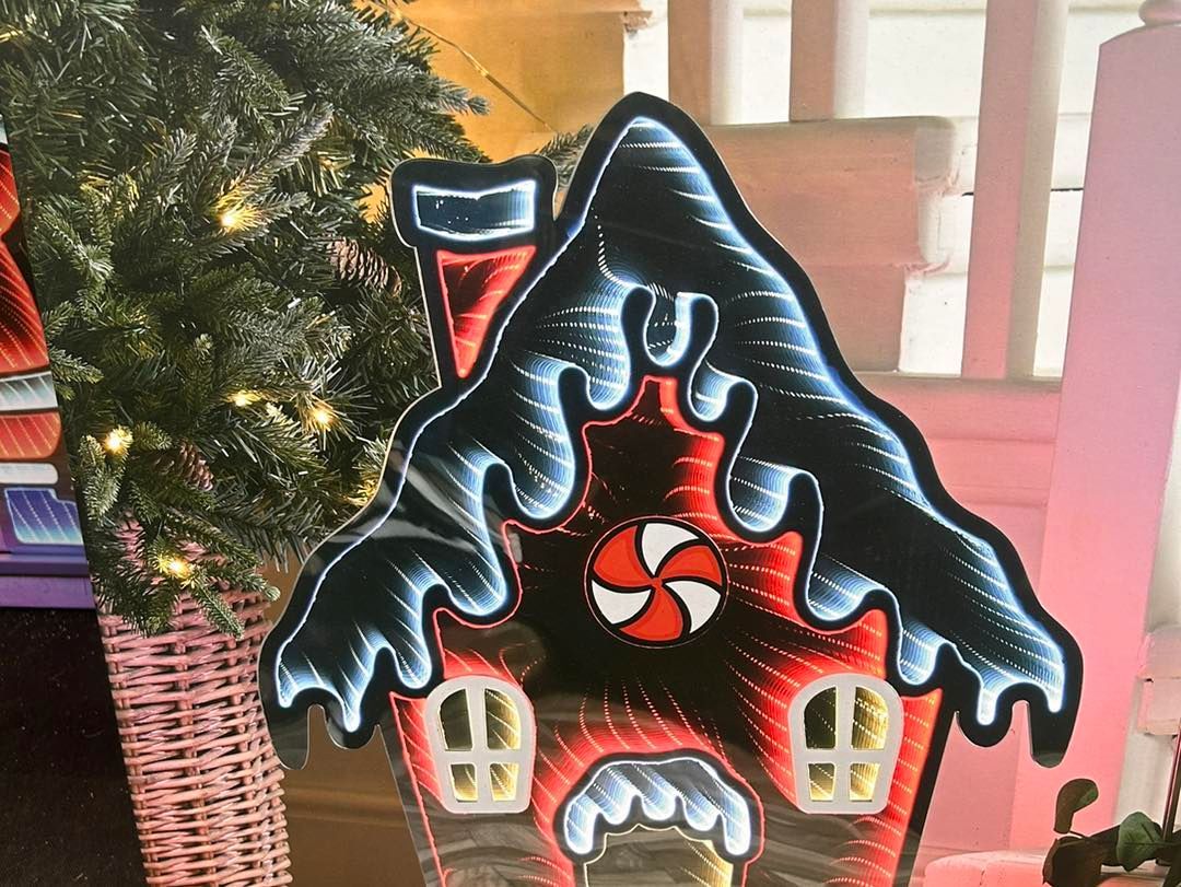 Gingerbread house decoration with red and white details, lit with white and blue lights.