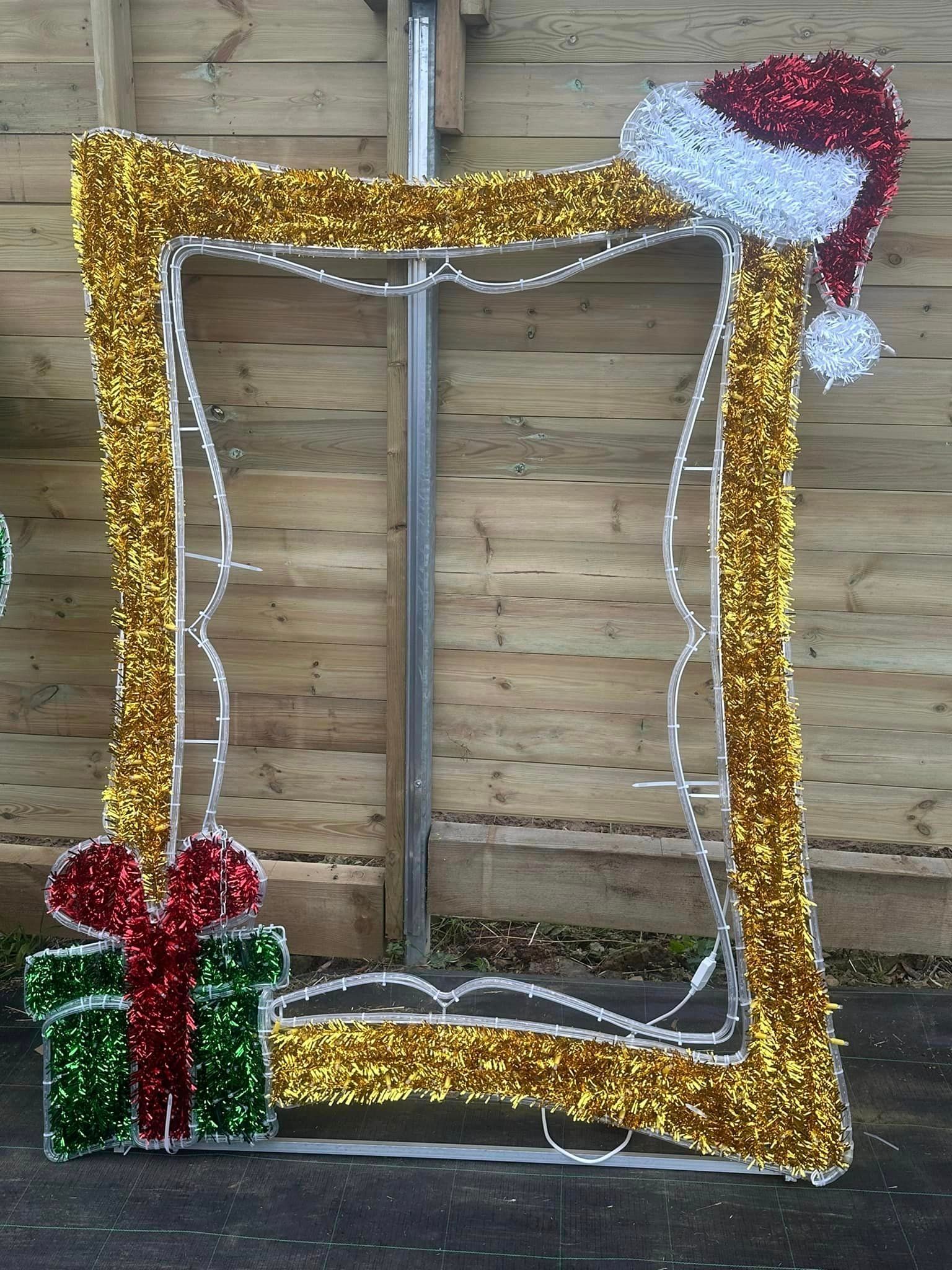 Christmas photo frame with gold lights, Santa hat, and gift.