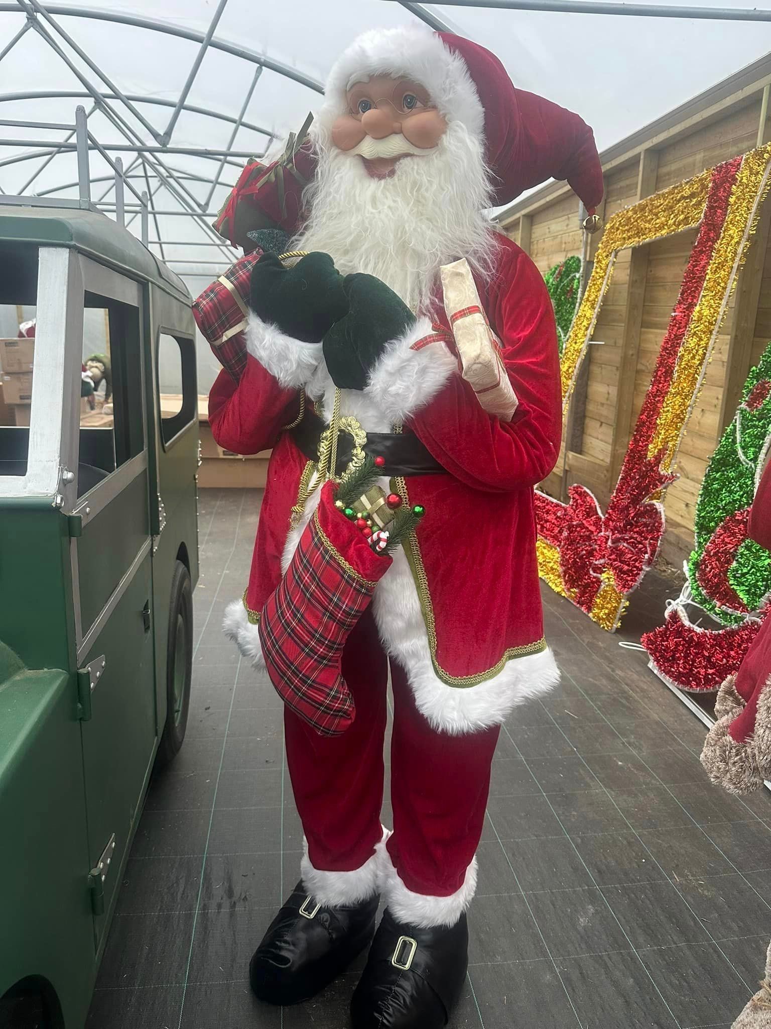 Santa Claus figure holding gifts, wearing a red suit, in a store.