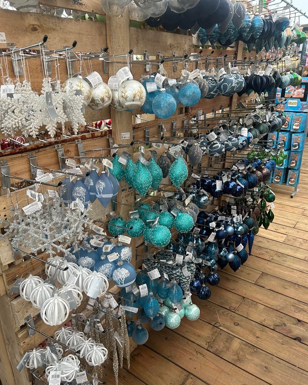 Christmas ornaments in various shades of blue and silver hanging on wooden shelves.