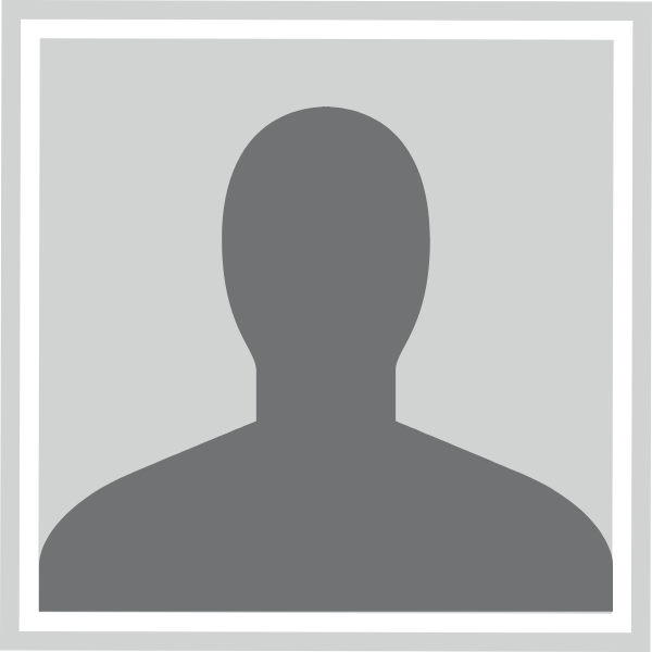 A woman in a black jacket and red shirt is smiling for the camera.