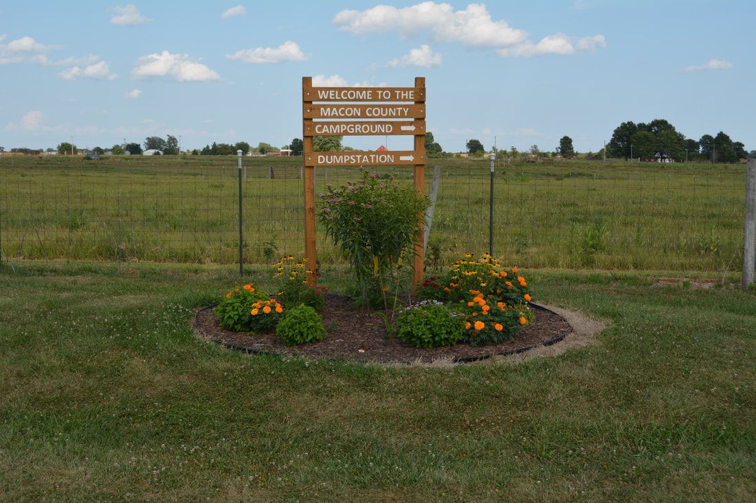 A wooden sign is sitting in the middle of a grassy field.