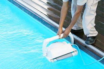 Swimming Pools Service & Repair — Worker Cleaning Pool with Pool Cleaner in Gainesville, FL