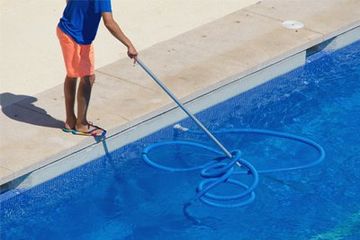 Swimming Pool Equipment & Supplies Dealers — Worker Cleaning Swimming Pool in Gainesville, FL