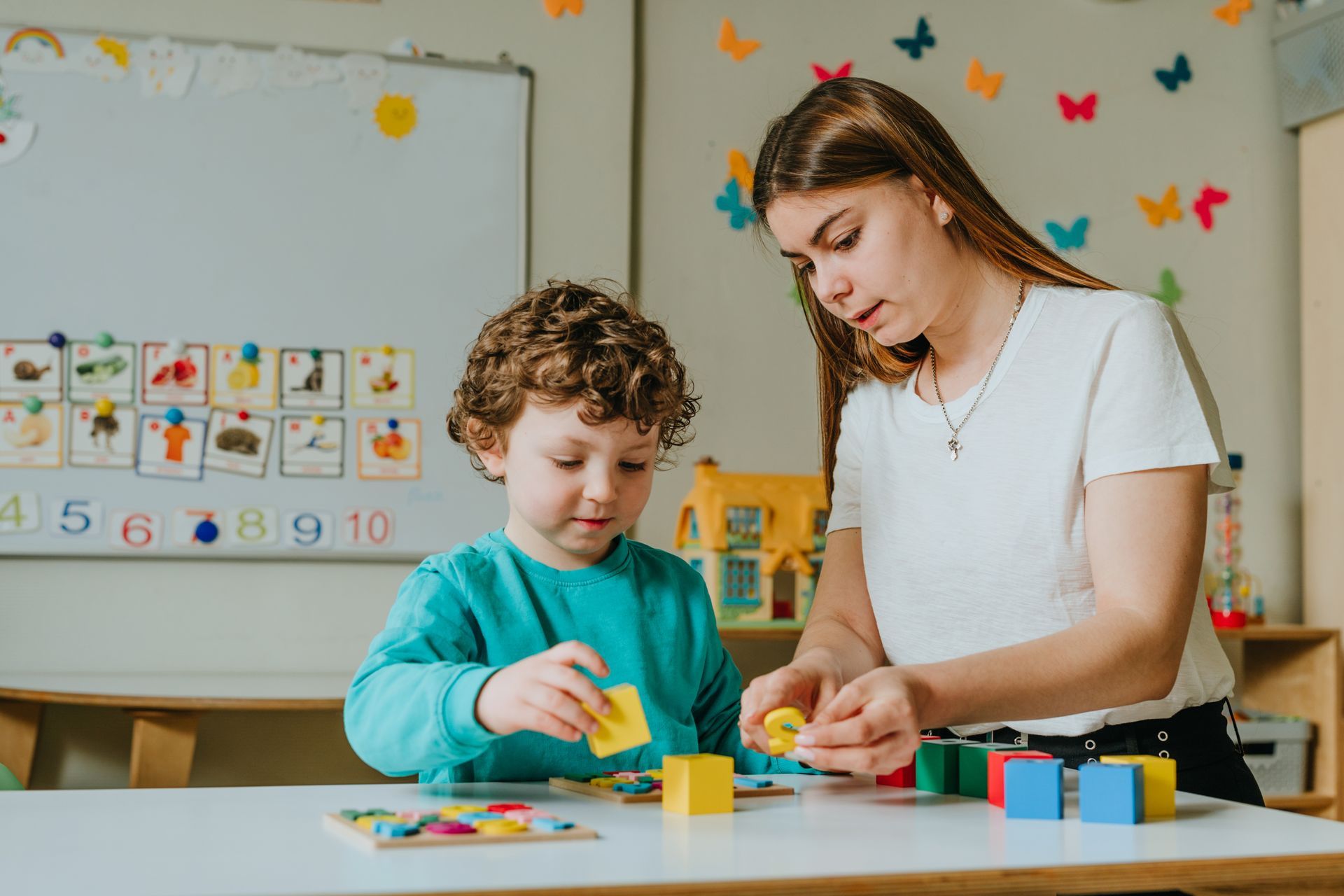 A woman and a child are playing with blocks at a table.