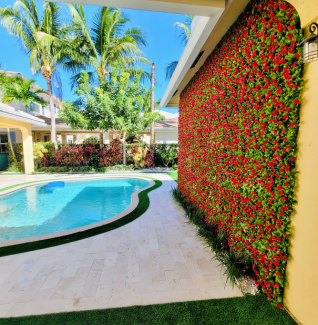 A swimming pool is behind a wall with red flowers on it in Jupiter, FL.