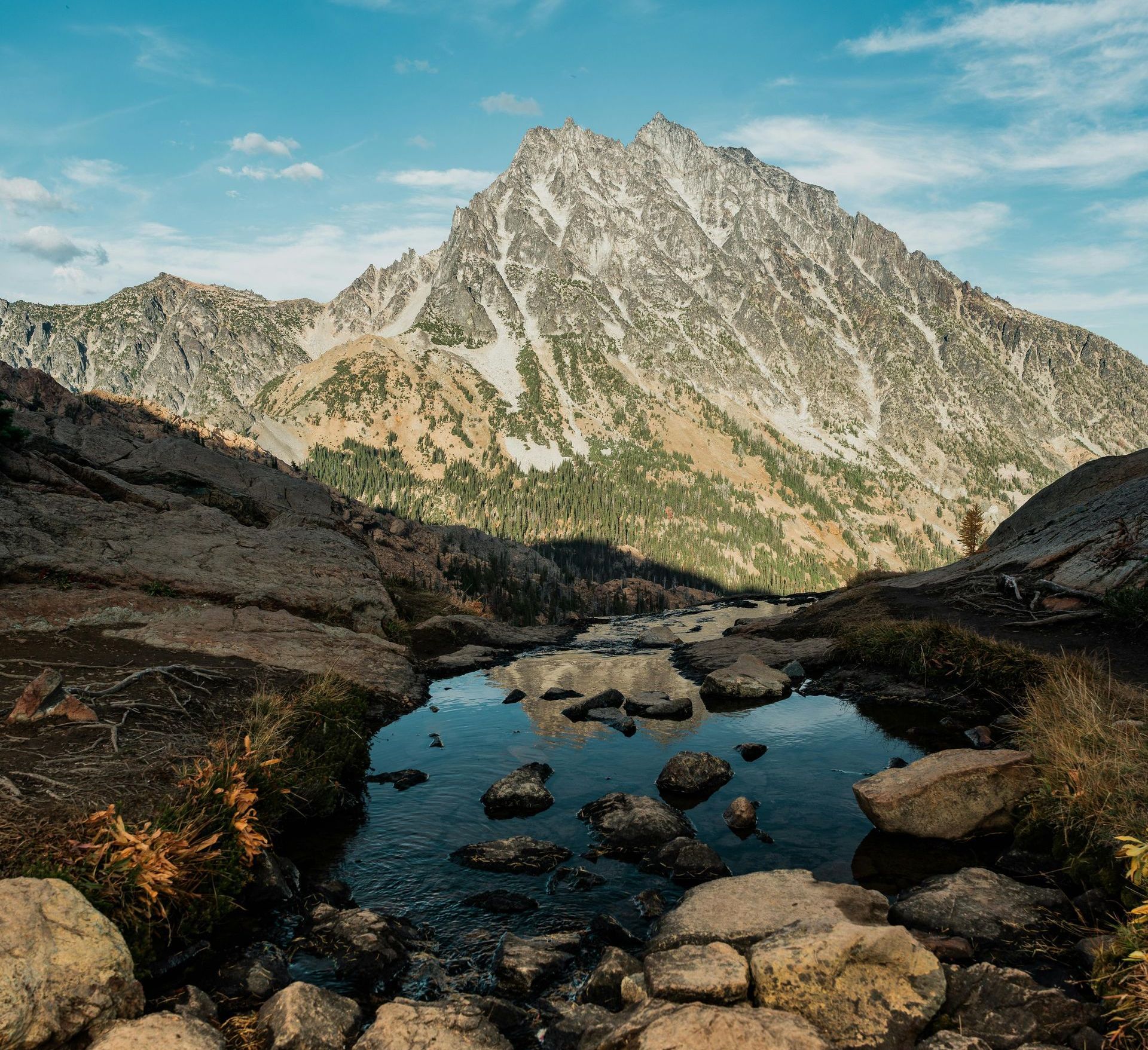 There is a river running through the mountains with a mountain in the background.