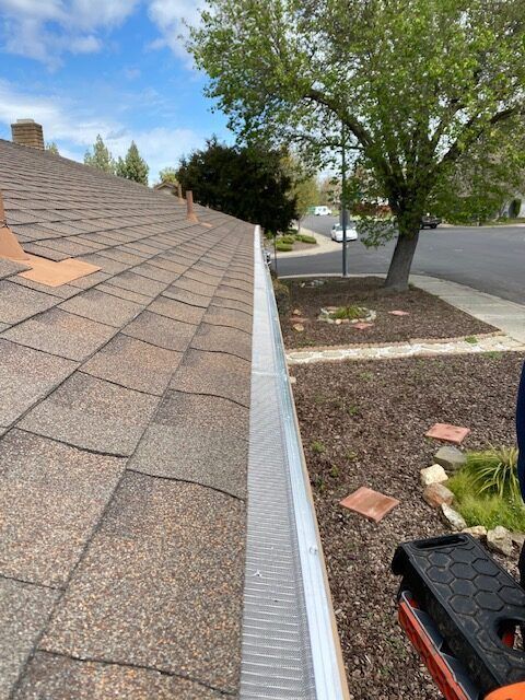 A person is working on a gutter on the roof of a house.