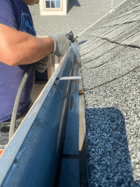 A man is working on a gutter on a roof.
