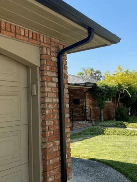 A brick house with a black gutter and a garage door.