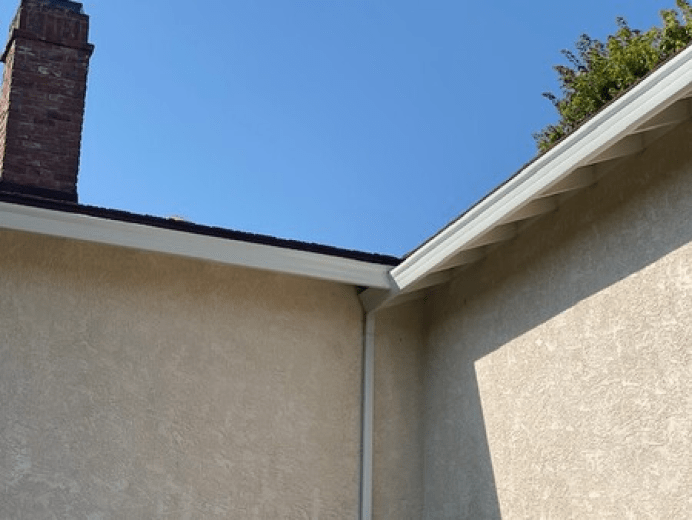The corner of a house with a chimney on top of it