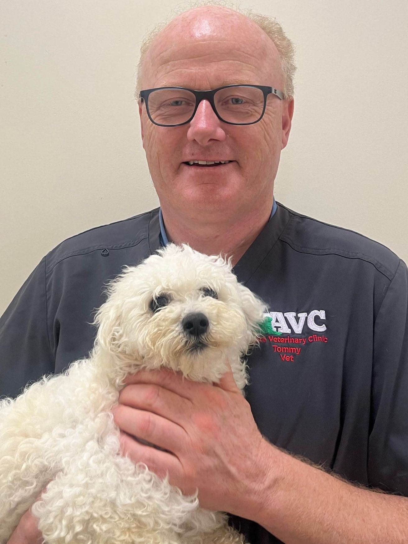 A man is holding a small white dog in his arms.