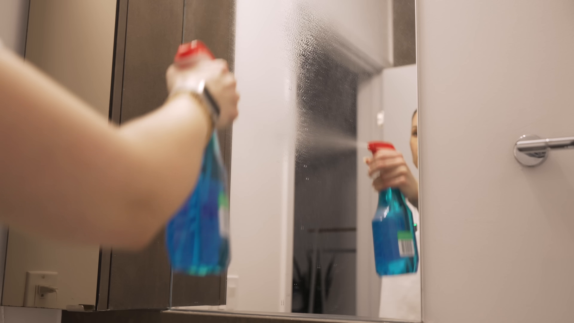 Woman wearing yellow gloves cleaning kitchen counter by a window.