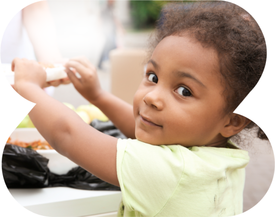 A little girl in a green shirt is looking at the camera