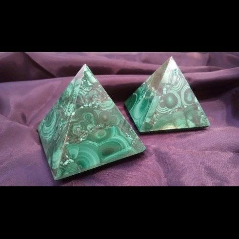Due piramidi verdi sono appoggiate su un telo viola.