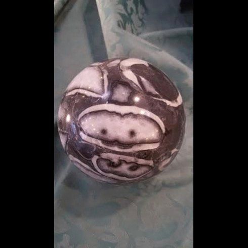 Una palla bianca e nera con una faccia è appoggiata su un tavolo.