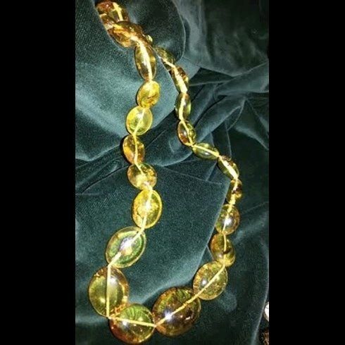 Un primo piano di una collana con perline gialle su un panno verde