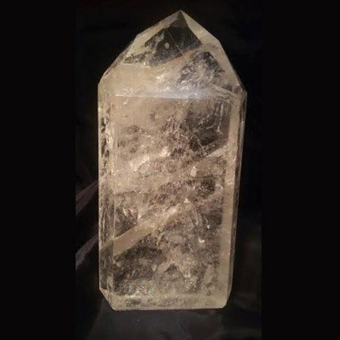 Una grande torre di cristallo trasparente è appoggiata su una superficie nera.