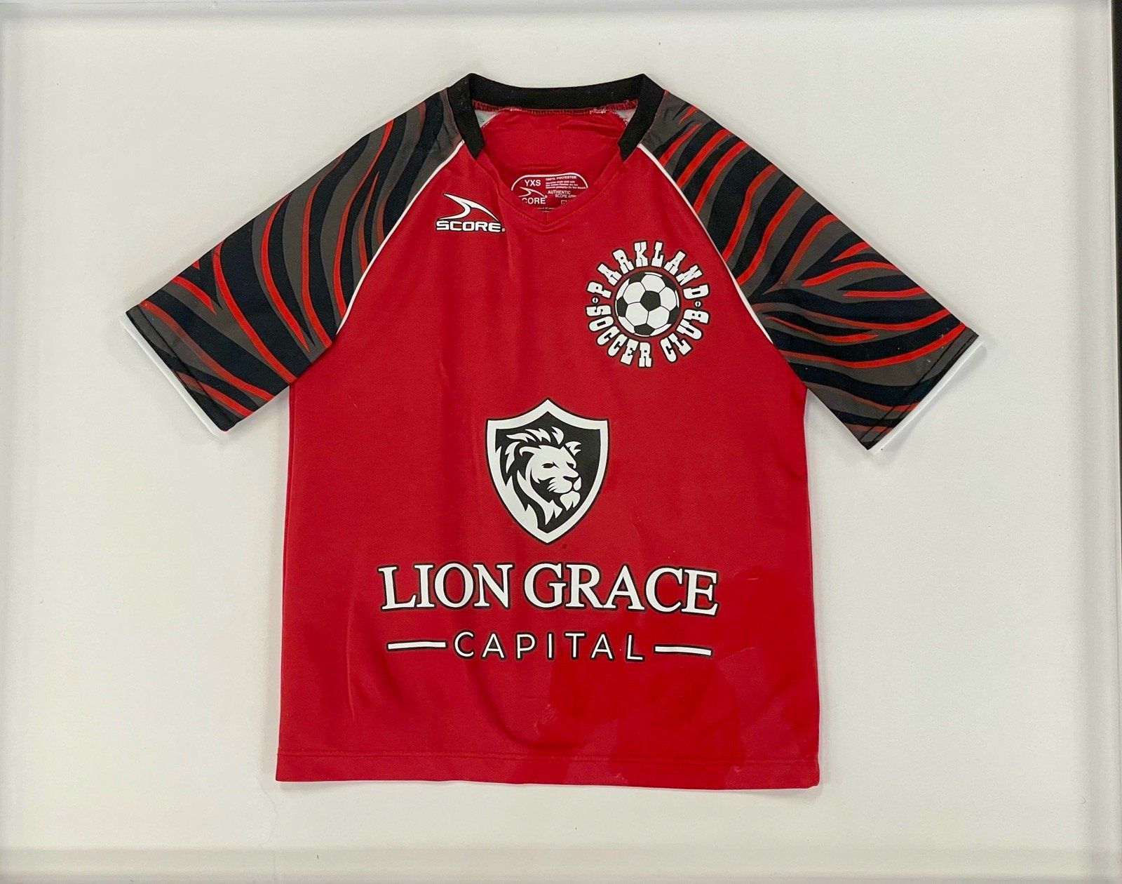A red shirt with a lion grace capital logo on it